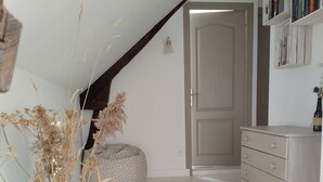 A room with a sloped ceiling, a wooden floor, a beige rug, a white dresser, and a bookshelf. - A vacation rental in the heart of Morbihan, nestled between land, river, and ocean! A guaranteed chance to recharge! (Saint-Dolay)