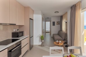 A modern kitchen with a microwave, oven, and a dining area with a table and chairs.