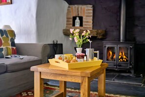 Ein gemütliches Wohnzimmer mit einem Holztisch, einer Couch, einem Kamin und einer Platte mit Gebäck.