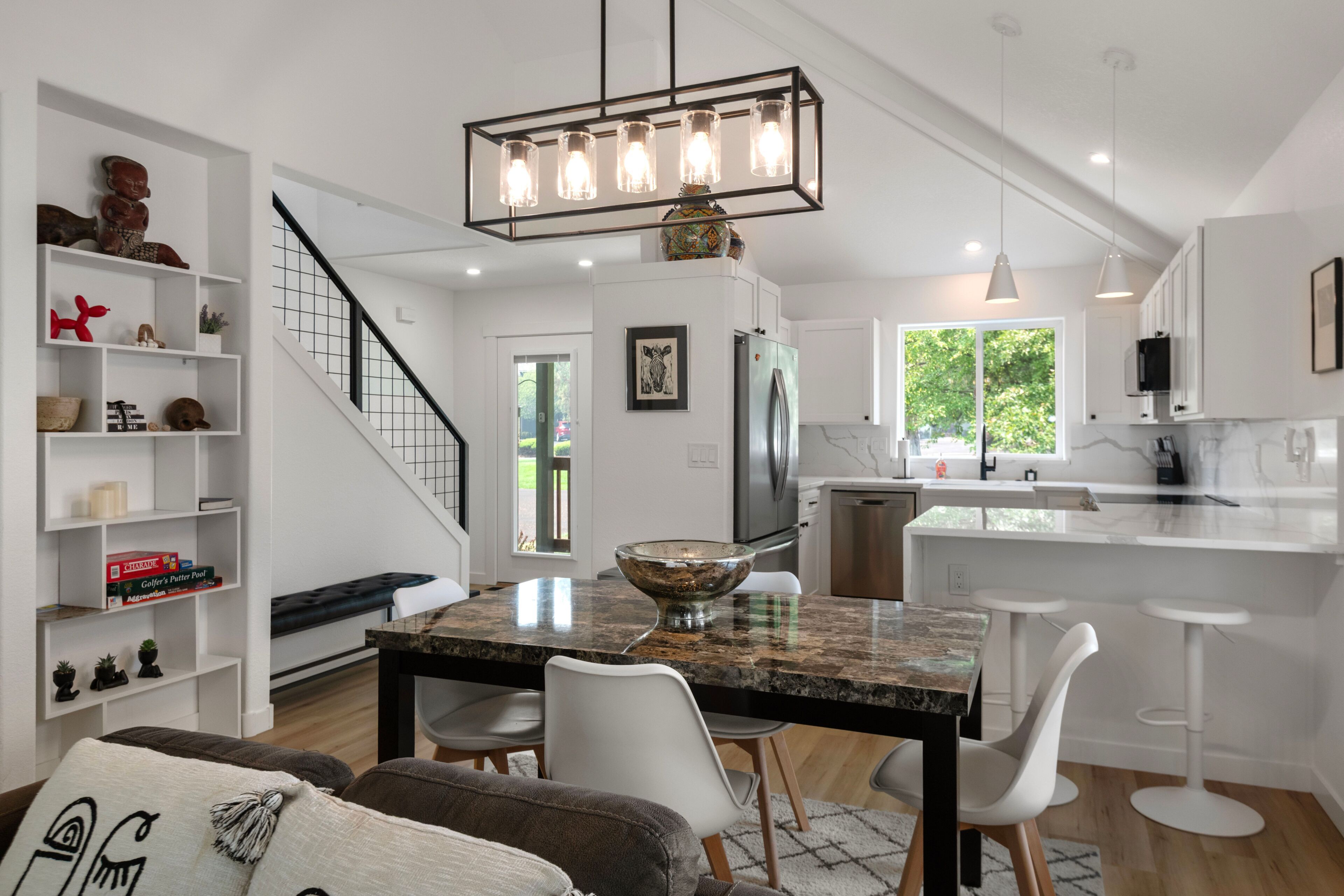 A modern kitchen with a central island, white cabinetry, and a stainless steel refrigerator.