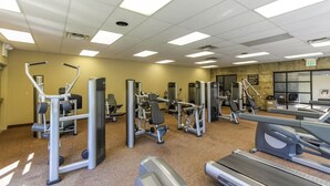 Ein Fitnessstudio mit verschiedenen Trainingsgeräten, Laufband und einer Spiegelwand.
