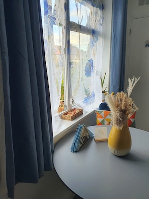 A room with a window, a vase with dried flowers, a small potted plant, and a basket on the windowsill. - Modern Studio SE9 | Free Parking | O2 & Greenwich (London)