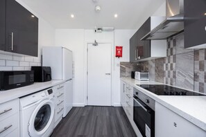 Cozinha moderna com máquina de lavar, micro-ondas, torradeira e fogão.