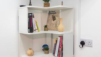 Estante branca com livros, um mapa e objetos decorativos.