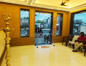 A reception area with a wooden interior, a decorative golden lamp, and a view of the street outside.