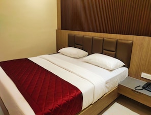A hotel room with a bed, a bedside table with a phone, and a wooden headboard.