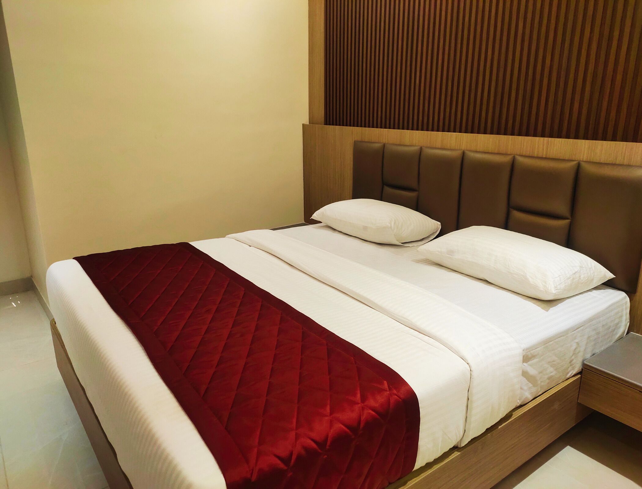 A bed with a red quilt, white linens, and a wooden headboard.