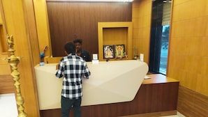 Un mostrador de recepción con detalles de madera, un cuadro religioso enmarco y una lámpara de latón.