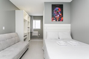 Ein modernes Hotelzimmer mit Bett, einer Sitzecke, einem Kleiderschrank und einem Fenster.