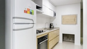 A modern kitchen with a built-in refrigerator, a microwave, a stove, and a coffee maker. - Apto Novo a 400m da Borges de Medeiros (Gramado)