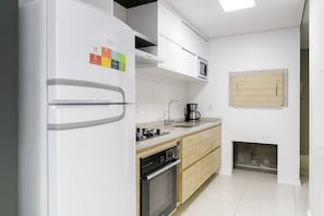 Uma cozinha moderna com frigorífico embutido, micro-ondas, fogão e máquina de café.