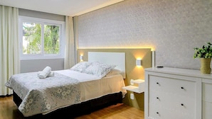 A bedroom with a bed, bedside tables, a dresser, and a window with curtains. - Apto Novo a 400m da Borges de Medeiros (Gramado)
