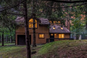 Ein zweistöckiges Holzhaus mit Garage, umgeben von Bäumen.