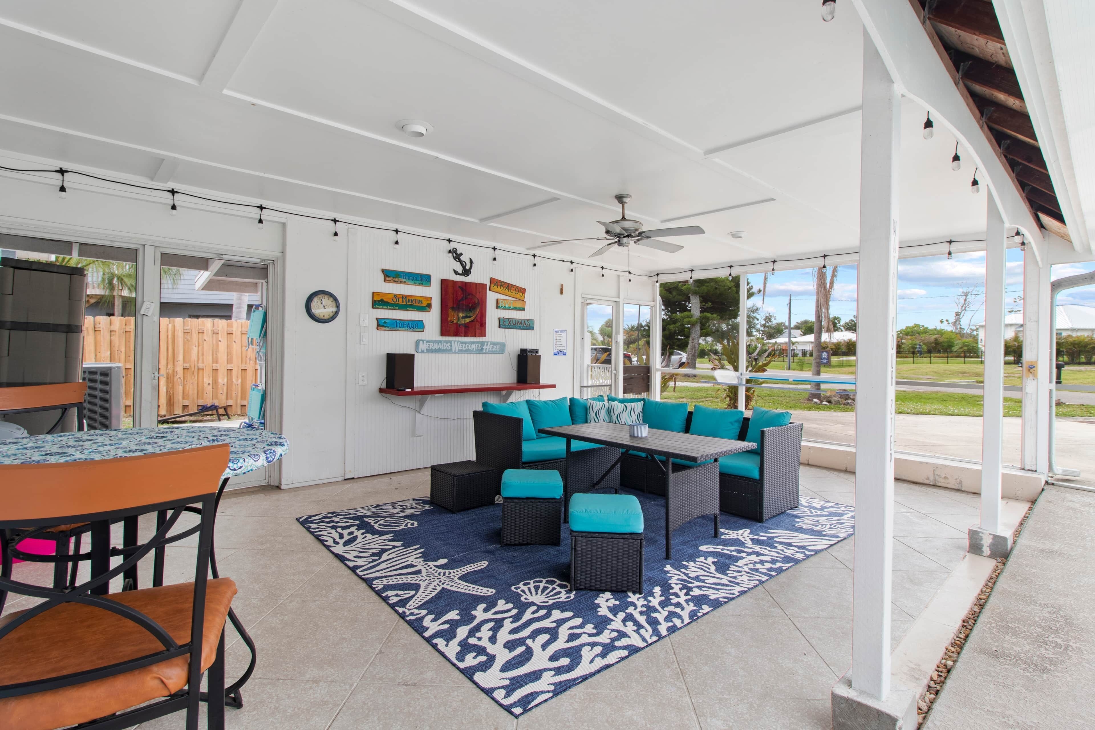 An outdoor patio with a dining area, seating, and a ceiling fan.