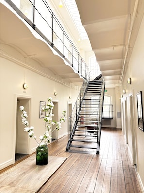 A spacious interior with a high ceiling, a staircase, and a large window allowing natural light. - Maj på Kronohäktet Karlskrona (Karlskrona)