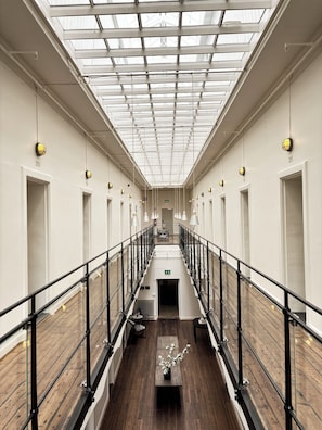 Ein Korridor mit Oberlicht, Holzboden und einer zentralen Treppe.