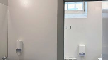 A bathroom with a black and white checkered floor, a white sink, and a window above the toilet.