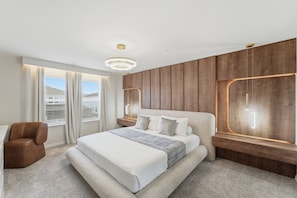 Ein modernes Schlafzimmer mit einem großen Bett, einer Wand mit Holzvertäfelung und Blick ins Freie.