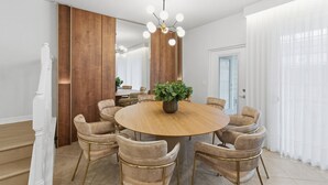 A modern dining room with a round wooden table, beige upholstered chairs, a central plant, and a ceiling light fixture. - 5BR Windsor Cay Home Near Disney, Pool & Games (Clermont)