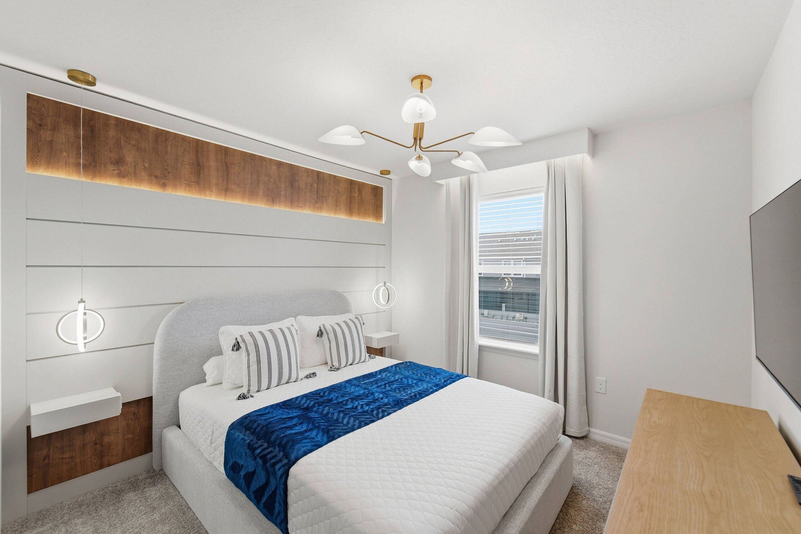 A bedroom with a bed, bedside tables, a desk, a ceiling light fixture, and a window with curtains.