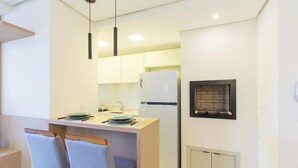 Eine moderne Küche mit einem eingebauten Kühlschrank, einer kleinen Essecke mit Tisch und Stühlen sowie einem Kamin.