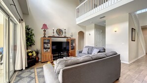 Una sala de estar con un sofá gris, un mueble de entretenimiento de madera y un balcón.