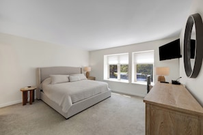 A bedroom with a bed, bedside tables, a TV, and a large mirror. - Steps to the beach & Salty Dog! 2 BR/2Bath Bluff Villa with all new furniture! (Hilton Head Island)