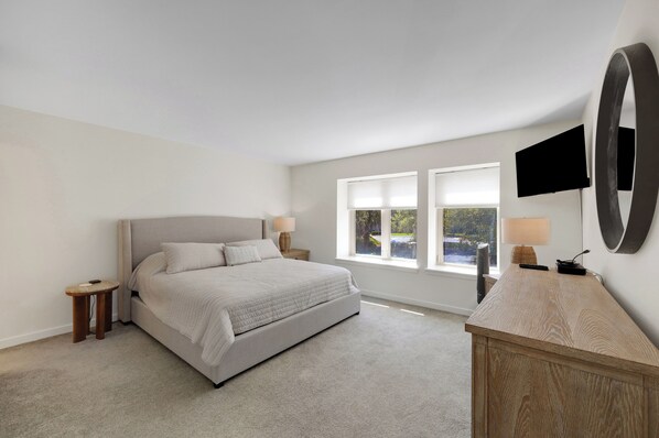 A bedroom with a bed, bedside tables, a TV, and a large mirror.