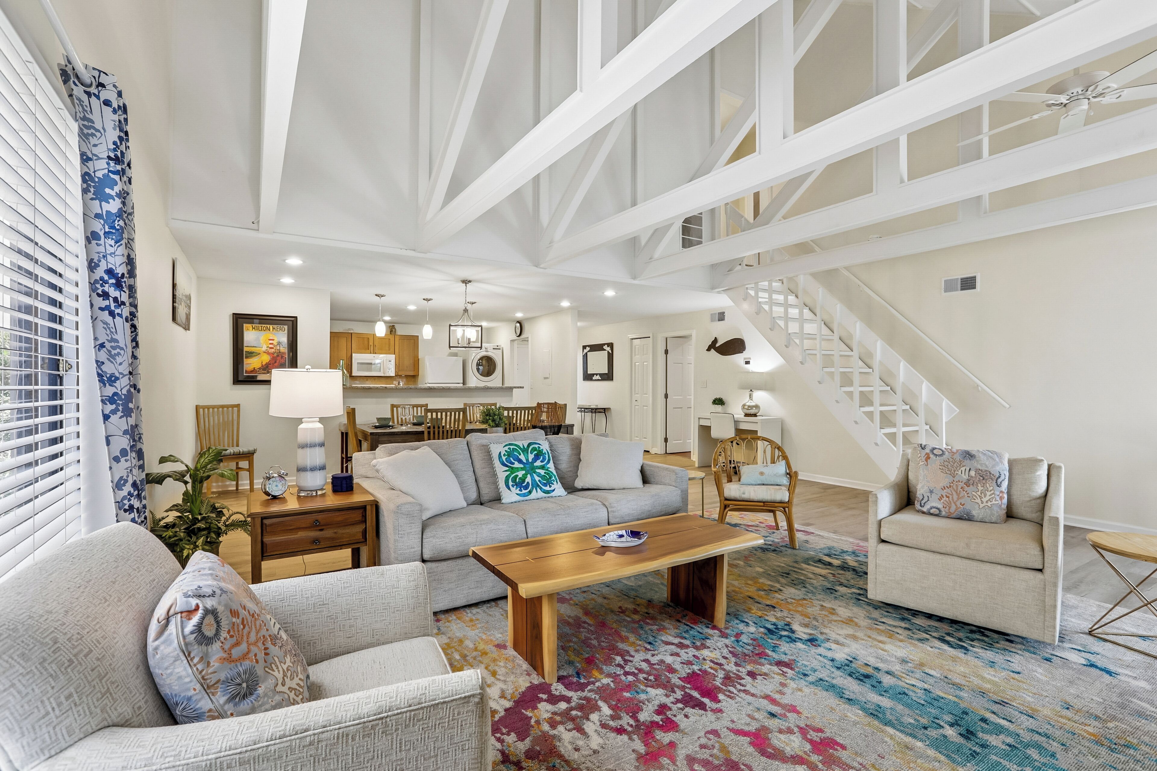 A spacious living room with a sofa, armchairs, a coffee table, and a patterned rug.
