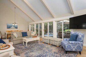 Ein geräumiges Wohnzimmer mit hohen Decken, großen Fenstern und modernem Interieur.