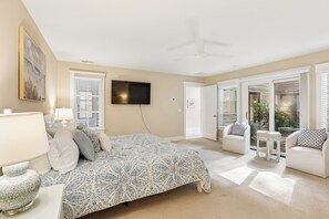 Ein Schlafzimmer mit einem Bett, einem Fernseher, einem Deckenventilator und Blick ins Freie durch eine Tür.