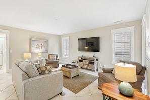A living room with a sofa, armchairs, a coffee table, a TV, and a painting on the wall. - Beautiful Home w/ Private Pool & Spa (Hilton Head Island)