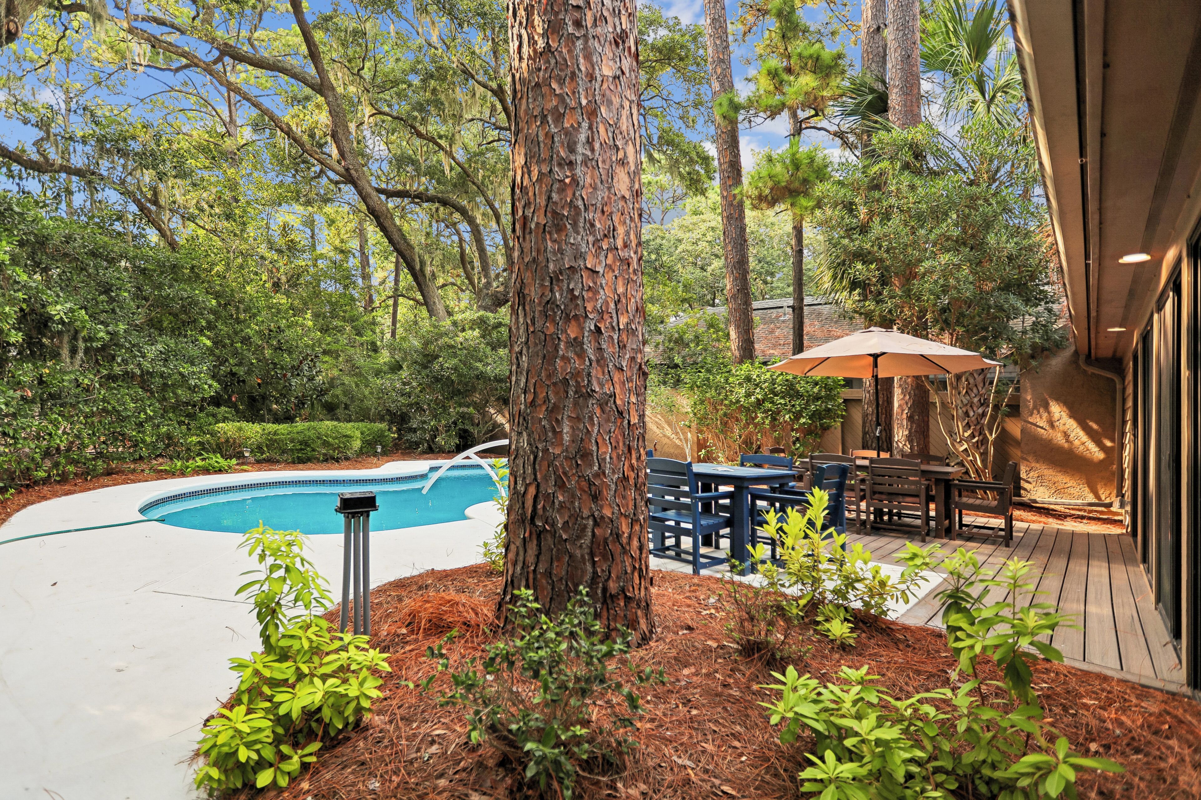 Un jardin avec une piscine, une terrasse en bois et du mobilier d’extérieur.