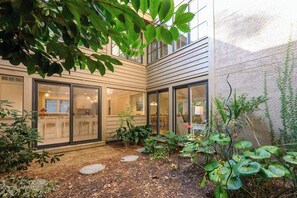 Ein modernes Haus mit Garten, großen Schiebegläsern und einem gepflasterten Weg.
