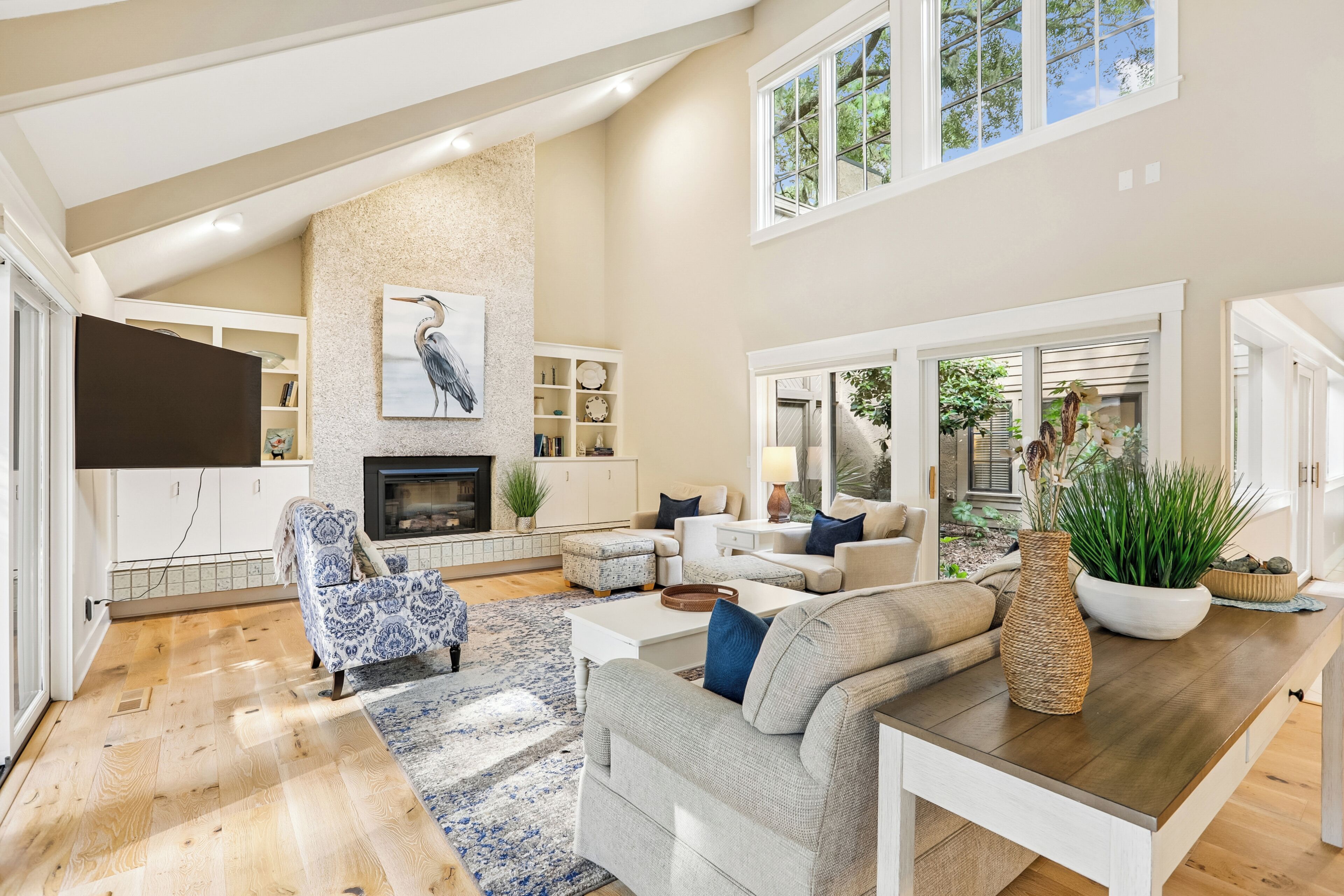A spacious living room with a fireplace, a television, and a large window overlooking greenery.