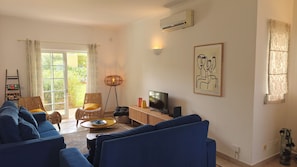 Un salon comprenant un canapé, un téléviseur, une lampe sur pied et un tableau accroché au mur.