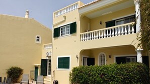 A two-story building with a swimming pool, a balcony, and a tiled patio area. - Villa lote 10 Paraiso da luz T4 (Luz)