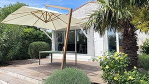 Una casa con patio, una sombrilla grande y una palmera.