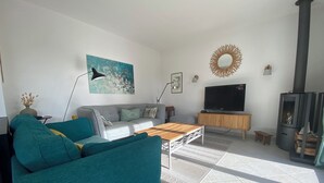 Una sala de estar con sofá, mesa de centro, televisor, chimenea y obras de arte en la pared.