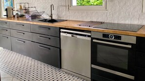 Una cocina moderna con lavavajillas, horno y ventana con vistas a zonas verdes.