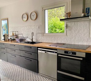 Eine moderne Küche mit Spülmaschine, Backofen und einem Fenster mit Blick ins Grüne.