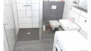 Un bagno moderno con doccia, WC e lavandino.