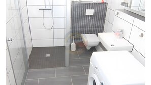 A modern bathroom with a shower, toilet, and sink. - Holiday Home Resterhafe in Dornum (Dornum)