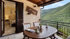 Una mesa de madera con sillas en un balcón con vistas a un paisaje montañoso.