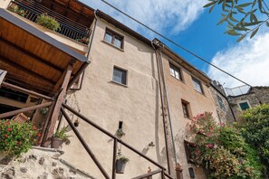 Un edificio con múltiples ventanales, un balcón de madera y macetas con plantas.