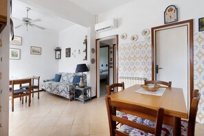 Ein Essbereich mit Holztisch, Stühlen, einem Deckenventilator und einer Wand mit Muster.