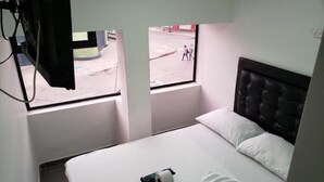 Ein Hotelzimmer mit Bett, Fenster und Blick auf die Straße.