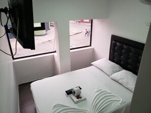 Ein Hotelzimmer mit Bett, Fenster und Blick auf die Straße.