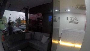 Et moderne interiør med en sofa, en glasvæg og en reception med skiltning.