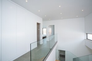 Ein modernes Interieur mit Glastrennwand, Treppe und Blick auf ein Schlafzimmer.
